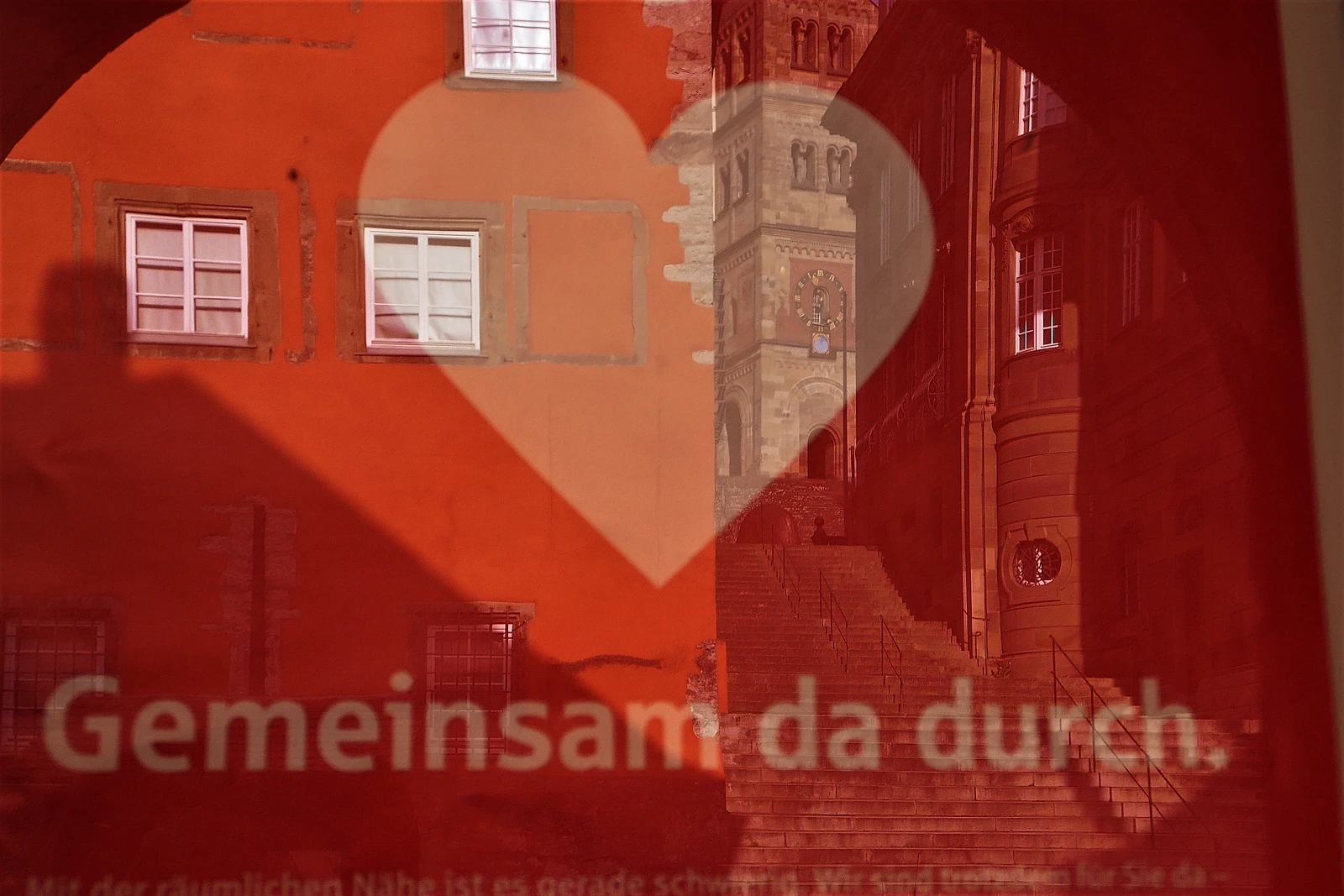 In der Schaufenster Aufschrift "gemeinsam da durch" spiegelt sich die Michaelskirche Schwäbisch Hall